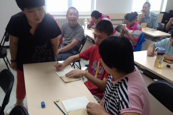 图为授课老师对残疾人学员进行指导