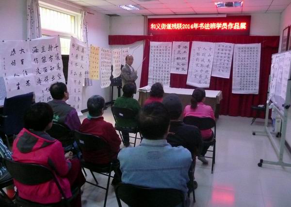 图为书法班老师点评残疾人学员书法作品