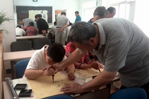 图为书法老师手把手指导残疾人