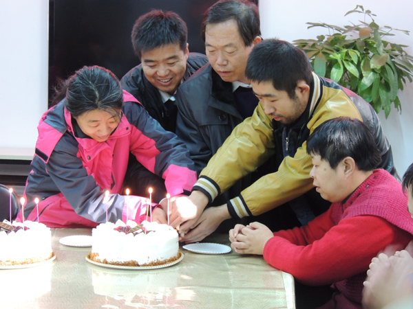 图为领导和残疾人共同切蛋糕