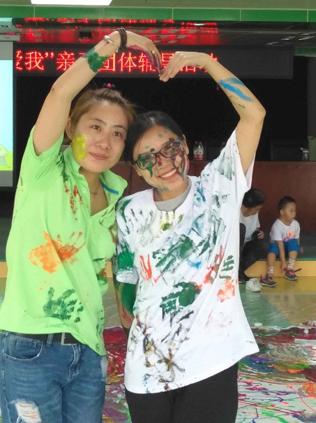 图为两位老师展示的体恤衫是孩子们涂鸦创意成果