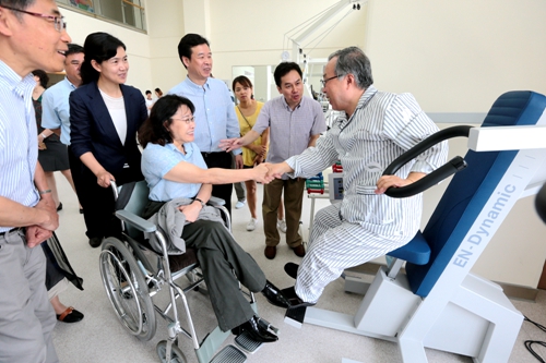 图为海迪主席与接受康复训练的患者亲切交谈，了解康复效果