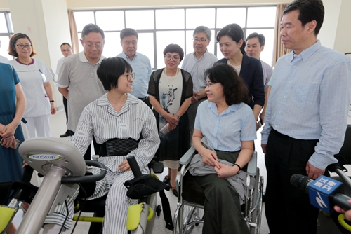 图为海迪主席与接受康复训练的患者亲切交谈，了解康复效果