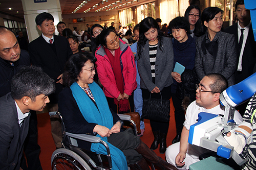 图为海迪主席听取康复医生技术工程人员关于上肢康复机器人结构和功能介绍