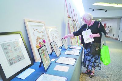 图为一名与会代表观看大会现场展出的中国残疾人艺术作品。光明日报记者 林卫光摄/光明图片