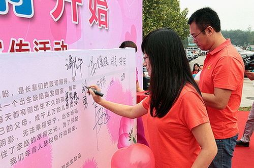图为青年夫妇代表在预防出生缺陷倡议书上签名