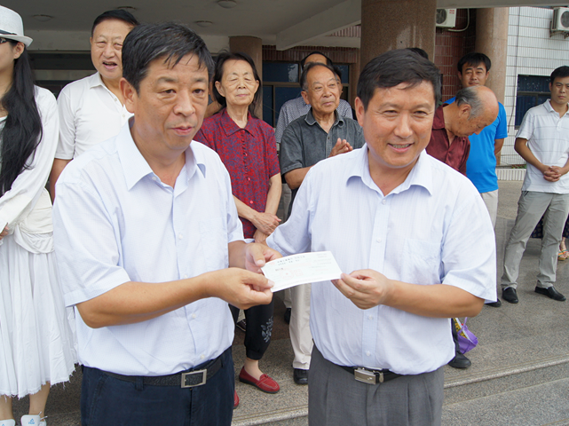 图为梁田向韩村河镇党委书记豆包才捐赠慰问款