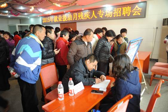 图为残疾人参加招聘会填写相关表格